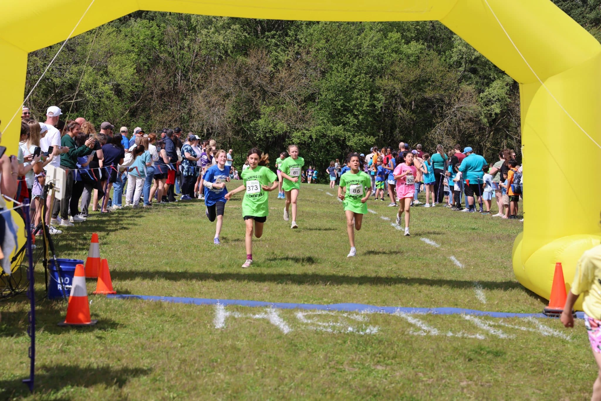 students cross finish line on a grass surface race
